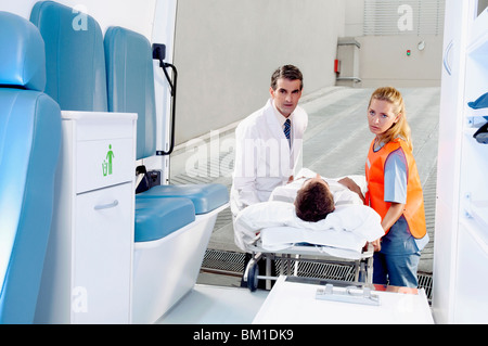 I paramedici spingendo un paziente su una barella da un'ambulanza Foto Stock