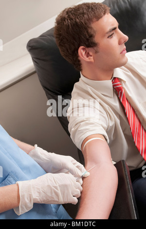 Medico tenendo campione di sangue di un uomo Foto Stock