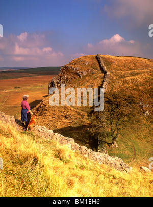 Donna che cammina cane il vallo di Adriano, parco nazionale di Northumberland, England, Regno Unito Foto Stock