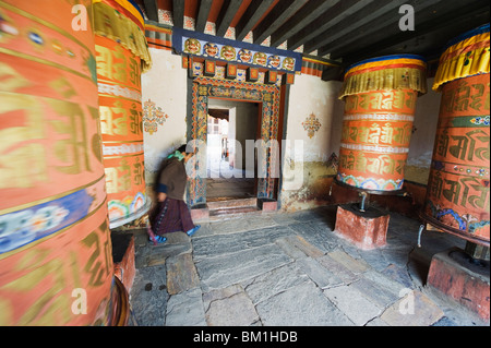 La donna la filatura di una ruota di preghiera, Jambay Lhakhang, costruito 659 dal re tibetano Songtsen Gampo, Jakar, Bumthang, Chokor Valley, Bhutan Foto Stock