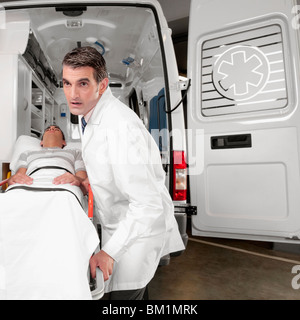 Medico spingendo un paziente su una barella da un'ambulanza Foto Stock