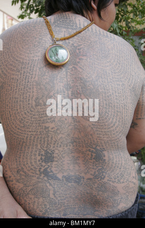 Un grasso giovane uomo si mette in mostra il suo tatuaggio durante il Wai Kru giorno al Wat Phra Bang, un tempio thailandese dove i monaci tattoo i loro devoti. Foto Stock