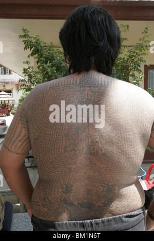 Un grasso giovane uomo si mette in mostra il suo tatuaggio durante il Wai Kru giorno al Wat Phra Bang, un tempio thailandese dove i monaci tattoo i loro devoti. Foto Stock