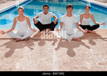 Quattro amici a praticare yoga a bordo piscina Foto Stock