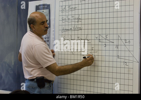 L'insegnante di geometria delle scuole superiori ispaniche scrive un problema su una lavagna bianca con linee grafiche su di essa alla Akins High School di Austin, Texas. ©Bob Daemmrich Foto Stock