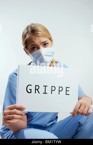 Ritratto di una donna chirurgo mostrando un cartello con la parola GRIPPE scritto su di esso Foto Stock