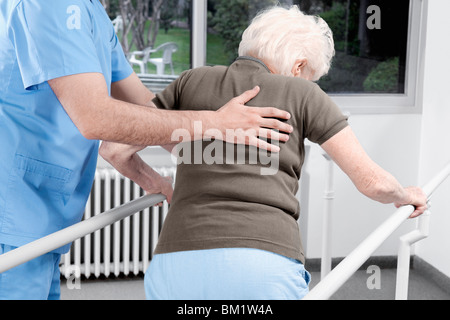 Lavoratore di salute assistere una donna disabile nel camminare Foto Stock