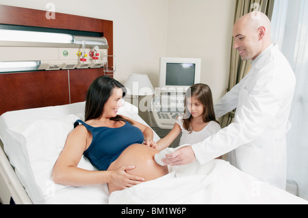 Donna incinta passando attraverso una scansione ad ultrasuoni con sua figlia guardando lei Foto Stock