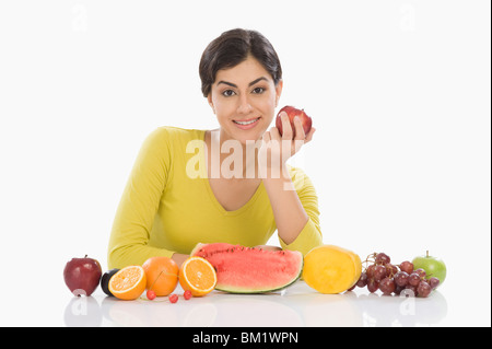 Ritratto di una donna con una fila di un assortimento di frutta fresca Foto Stock