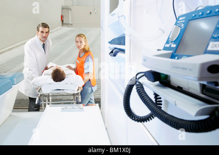 I paramedici spingendo un paziente su una barella da un'ambulanza Foto Stock