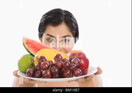 Ritratto di una donna tenendo un piatto di frutti assortiti Foto Stock