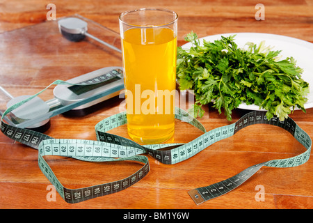 Bicchiere di succo di frutta con una scala di pesatura e un nastro di misurazione Foto Stock