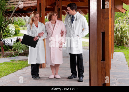 I medici che assiste un paziente a camminare in un centro di riabilitazione Foto Stock