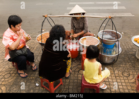 Donne locali godendo di caramelle da un semplice streetstall su Hau Giang Street. Foto Stock