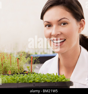 Donna scienziato sorridendo vicino impianti in un laboratorio Foto Stock