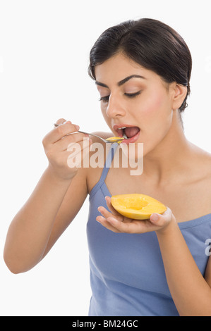 Close-up di una donna di mangiare il mango con un cucchiaio Foto Stock