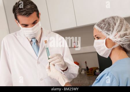 Tecnici di laboratorio analisi di un campione in un tubo di prova Foto Stock