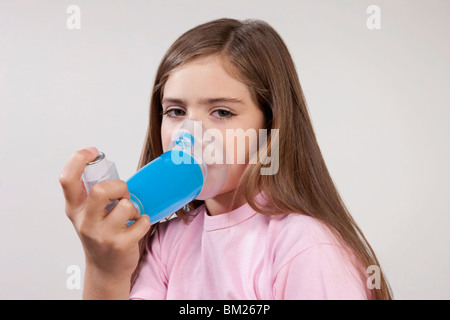 Ragazza con un inalatore per asmatici attaccato con un distanziale Foto Stock