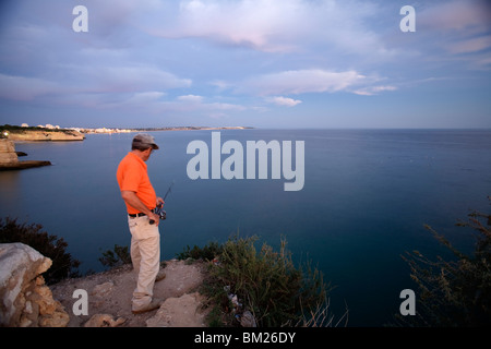 Pescatore sulla cima di una scogliera, città di portici, comune di Lagoa, distretto di Faro, regione di Algarve, PORTOGALLO Foto Stock