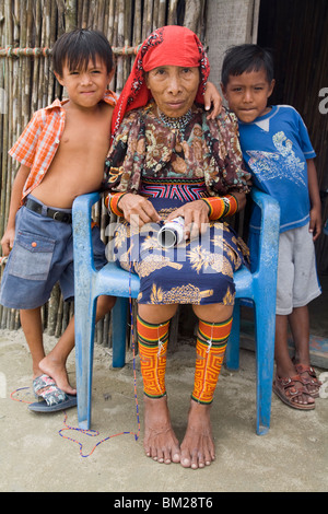 La Kuna famiglia al di fuori della loro casa di paglia, Isla Tigre, isole San Blas, Comarca de Kuna Yala, Panama Foto Stock