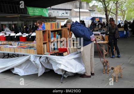 Uomo con due cani esplorazione del libro si spegne sul South Bank di Londra city centre REGNO UNITO Foto Stock