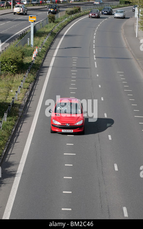 Un auto rossa passa al di sopra di velocizzare i contrassegni e passato un Gatso autovelox sulla A316, grande Chertsey Road, Hounslow, Regno Unito. Foto Stock