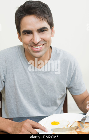 Ritratto di un uomo avente la colazione su un tavolo da pranzo Foto Stock