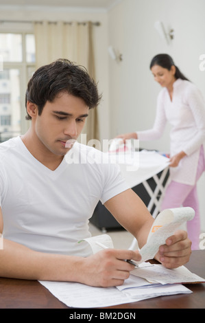 Uomo di smistamento di fatture con una donna la stiratura di panni Foto Stock