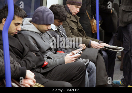 MESSAGGI DI TESTO SUI VECCHI TELEFONI CELLULARI, 2010: Metropolitana metropolitana di Londra pendolari treno pendolari persone viaggiano viaggiando stanchi pendolari strada a casa lavoro Foto Stock