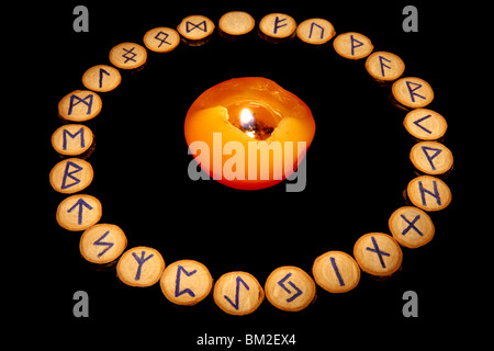 Rune impostato intorno a candela in classico ordine alfabetico 'futhark'. Isolato su sfondo nero Foto Stock