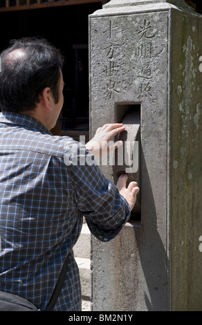 L'uomo la filatura di una ruota di preghiera al Tempio Zenkoji, Nagano City, Giappone Foto Stock