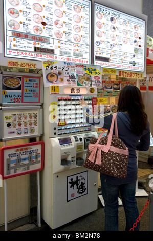 Donna acquistando i biglietti per i pasti da un distributore automatico in un ristorante a Dotonbori, Osaka, Giappone Foto Stock