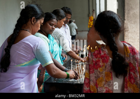 Adoratori di illuminazione candele di Preghiera nella Basilica del Bom Jesus nel vecchio Goa, India Foto Stock