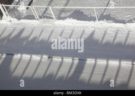 OMBRE SU STRADA NEL PROFONDO INVERNO DELLA FINLANDIA: Ombre ombra inverno coperto di neve ghiacciato marciapiede marciapiede Kajaani Finlandia centro città Foto Stock