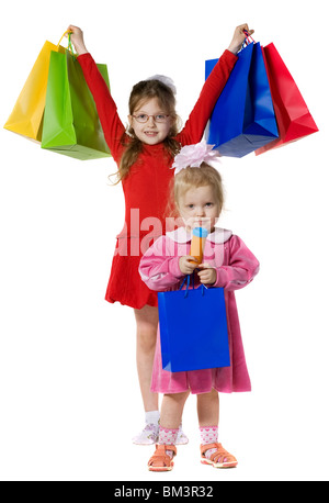 Due bambine in rosso e rosa vestiti con le confezioni colorate con acquisti, isolato su bianco Foto Stock