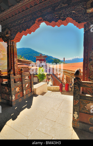 Vista dal tempio oltre il cortile con i monaci e uomo in abito nazionale, Trongsa Dzong, Bhutan. Foto Stock