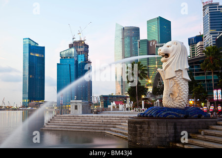 La statua Merlion con lo skyline della città in background, Esplanade, Singapore Foto Stock