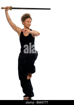Donna matura praticing tai chi chuan con la spada in studio isolato su sfondo bianco Foto Stock