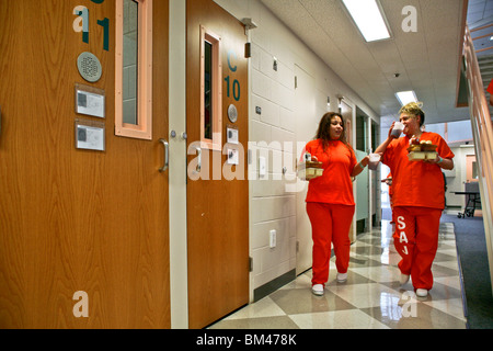 Due ispanici detenuti in Womens unità camera di giorno della Santa Ana, California, City Gaol portano i loro singoli-porzione al sacco. Foto Stock