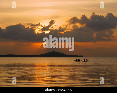 Piccola pesca motoscafo scivola nella parte anteriore del Koh Phangan island al tramonto, Thailandia. Vista dal Mae Nam Beach, Koh Samui Island. Foto Stock