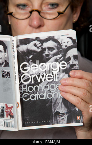 Donna leggendo una copia di George Orwell di Omaggio alla Catalogna pubblicato da pinguino Foto Stock