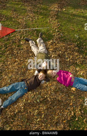 Bambini rilassante in un mucchio di foglie di autunno Foto Stock