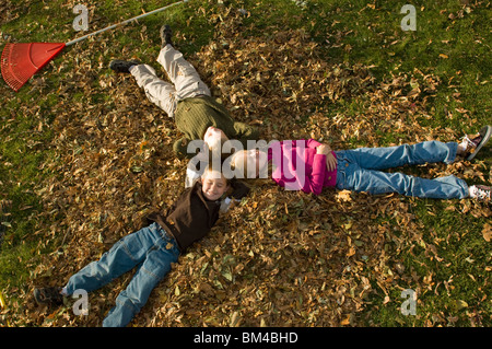 Bambini rilassante in un mucchio di foglie di autunno Foto Stock