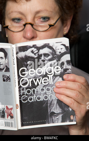 Donna leggendo una copia di George Orwell di Omaggio alla Catalogna pubblicato da pinguino Foto Stock