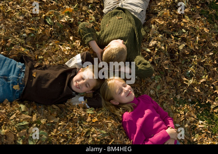 Bambini rilassante in un mucchio di foglie di autunno Foto Stock