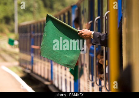 Una guardia mostra una bandiera verde sulla carreggiata stretta Nilgiri ferrovia di montagna in Tamil Nadu, India. Foto Stock