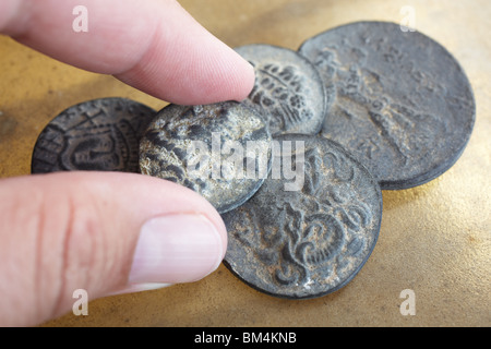 Un uomo azienda antico greco-romana antica monete provenienti dalla Turchia, su una pelle liscia foglio dello sfondo. Foto Stock