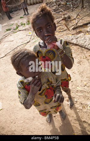 Due ragazze nel villaggio di ceramiche di Kalabougou vicino a Segou, Mali sorseggiare bevande congelate dalla plastica blags. Foto Stock