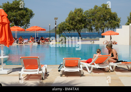 I villeggianti rilassarsi intorno a una piscina in albergo nella località balneare di Turgutreis vicino a Bodrum Turchia Foto Stock