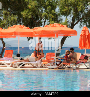 Due coppie relax intorno a una piscina in albergo nella località balneare di Turgutreis vicino a Bodrum Turchia Foto Stock